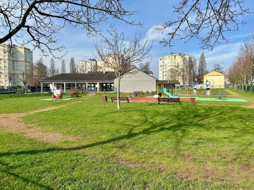 a park with a tree and a playground at Le rêve Bleu in Thionville