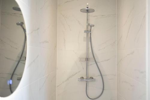 a shower in a bathroom with white marble walls at Grand Central Suites in Zandvoort
