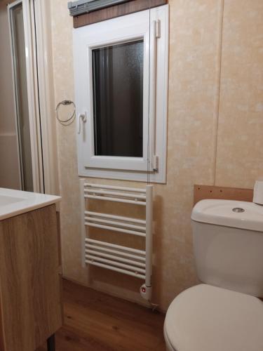 uma casa de banho com WC e uma televisão na parede em Mobil home willerby de luxe em Le Portel