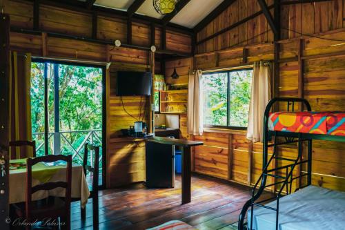 a room with a desk and a bed in a wooden cabin at Hospedaje La Naciente in Turrialba