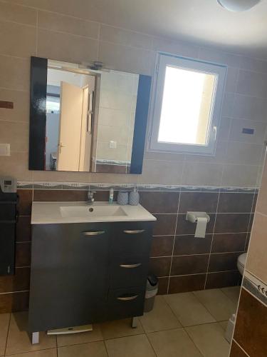 une salle de bain avec un lavabo et un miroir dans l'établissement Petit Coin du Port, à Ploubazlanec