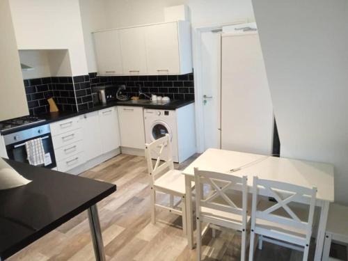 a kitchen with white cabinets and a table and chairs at Double-bed (G4) close to Burnley city centre in Burnley