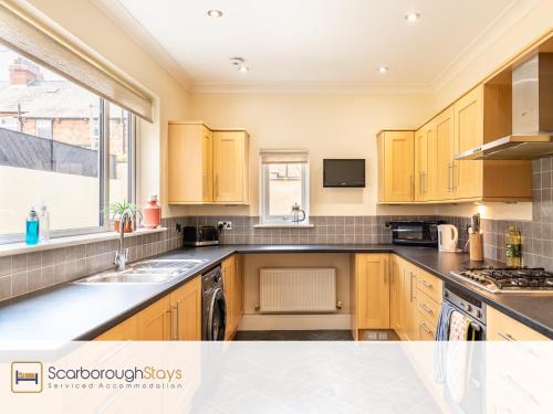 a kitchen with wooden cabinets and a sink and a window at Mayville Lodge - STUNNING 3 BEDROOMED TOWNHOUSE WITH FREE PARKING in Scarborough
