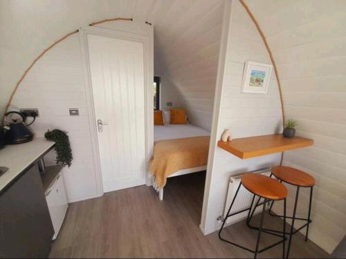 Habitación pequeña con cama, mesa y taburetes en The Nest, en Doolin