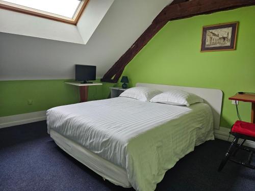 een slaapkamer met een bed met een groene muur bij Cafe de la croix morzel in Cordemais