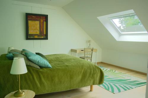 ein Schlafzimmer mit einem grünen Bett und einem Fenster in der Unterkunft Le gîte Marie-Galante : Belle maison d'hôtes avec accès piscine en été in Lanmeur