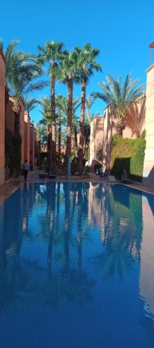 a large swimming pool with palm trees in the background at Riad Nour Resorts-Riad Nour Travel in Marrakech
