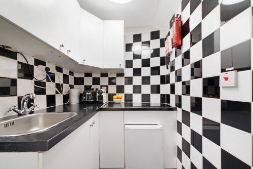 uma cozinha com um lavatório e uma parede xadrez em Little Venice Studio By Morethanstays em Londres