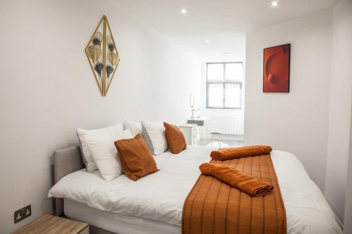 Cityscape 2-BR - Leicester's Premier Urban Retreat في ليستر: سرير أبيض مع وسائد بنية اللون فوقه