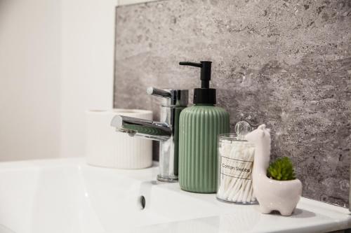 a bathroom sink with a green bottle of soap and a soap dispenser at Cityscape 2-BR - Leicester's Premier Urban Retreat in Leicester