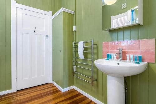 a green bathroom with a sink and a white door at Riverhead Villa with BBQ and deck in Riverhead