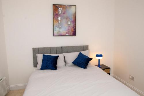 a bedroom with a large white bed with blue pillows at Luxury 2 bed flat in Northampton in Northampton