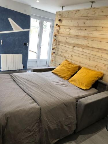 - une chambre avec un grand lit et 2 oreillers jaunes dans l'établissement Rez de jardin Cosy entre Disney et Paris, à Lagny-sur-Marne