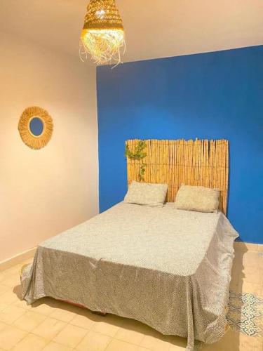 een slaapkamer met een bed met een blauwe muur bij apartment a ksar sghir in front Tanger Med ferry port in Agaouz