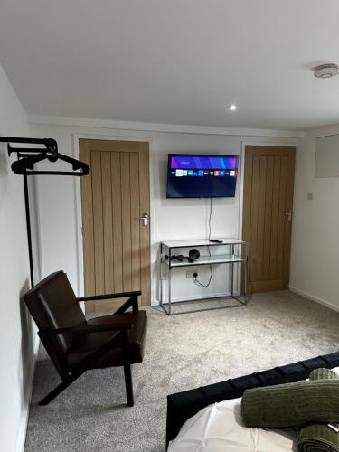 sala de estar con silla y TV de pantalla plana en Entire Apartment super king bed close to Town Centre en Colchester
