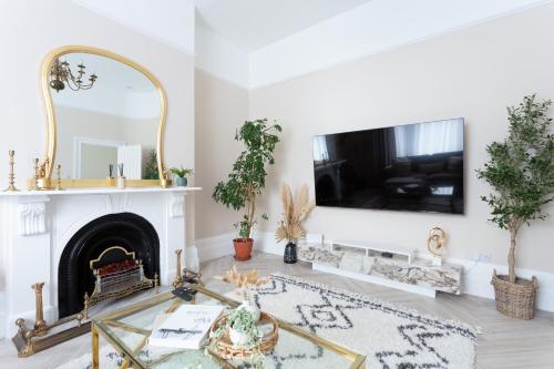 uma sala de estar com lareira e uma televisão na parede em Stunning Large 4 Bedroom Victorian Home London em Londres