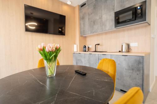 a black table with yellow chairs and a vase of flowers at Apartament z Tarasem Morska 6 Rewal 50m do morza in Rewal