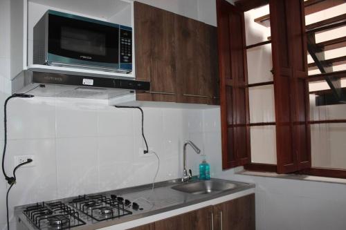 - une cuisine équipée d'un évier et d'un four micro-ondes au-dessus d'une cuisinière dans l'établissement Casa en la Candelaria con Gran Terraza Privada, à Bogotá