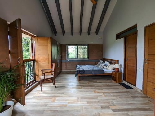 a bedroom with a bed and a chair in a room at Red Rock Villa, Virajpet, Coorg in Virajpet