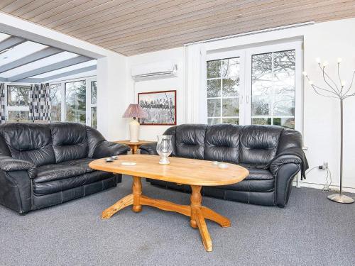 Fjellerupにある10 person holiday home in Glesborgのリビングルーム(黒い革張りのソファ、木製テーブル付)