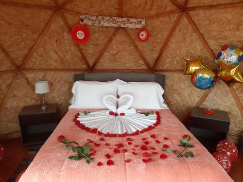 a bed with a bunch of red roses on it at El Rodeo Glamping in Toca