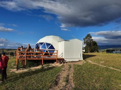 un observatorio abovedado en un campo con gente a su alrededor en El Rodeo Glamping en Toca