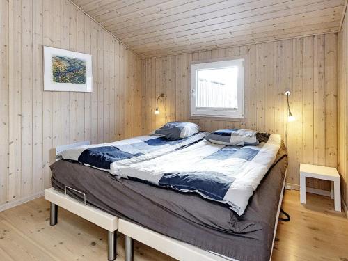 Holiday home Fjerritslev XXXVII في Fjerritslev: غرفة نوم بسرير كبير في غرفة بجدران خشبية