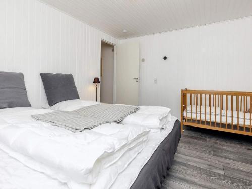 a large white bed in a bedroom with a crib at Holiday home Oksbøl XII in Oksbøl