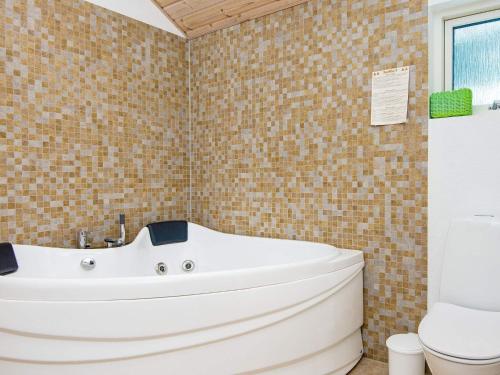 a bathroom with a white tub and a toilet at Three-Bedroom Holiday home in Silkeborg 3 in Dalsgårde