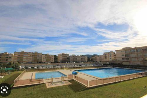 une grande piscine avec des bâtiments en arrière-plan dans l'établissement MARCO POLO - studio neuf avec parking & piscines, à Mandelieu-la-Napoule