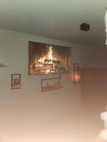 a tv hanging on a wall with a fire in it at Le relax in La Louvière