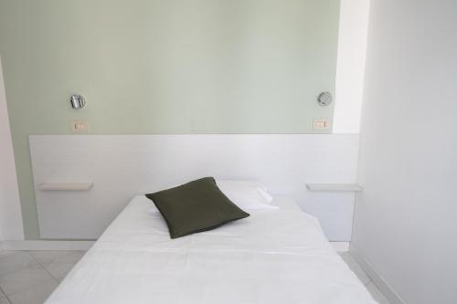 a white bed with a black pillow on it at Hotel The Sea in Rimini