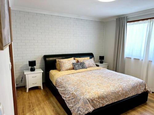 - une chambre avec un grand lit et 2 tables de chevet dans l'établissement 3 Bedroom Holiday Townhouse @ Belconnen, à Belconnen