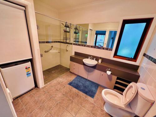 a bathroom with a toilet and a sink and a shower at A Lovely Pool House in Forest in Wonga Park