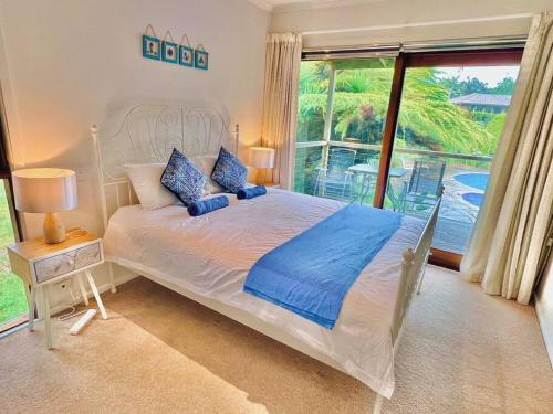 a bedroom with a bed and a large window at A Lovely Pool House in Forest in Wonga Park