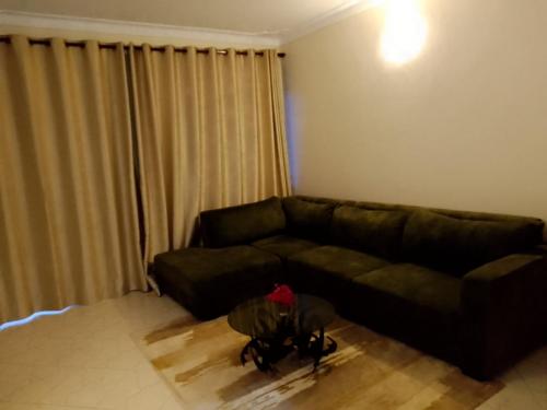 - un salon avec un canapé noir et une fenêtre dans l'établissement Zen in Ibanda, à Kitwe