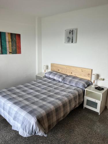 ein Schlafzimmer mit einem großen Bett mit einer karierten Decke in der Unterkunft Ático El Faro Cullera in Faro de Cullera