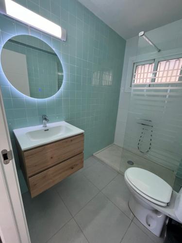 ein Badezimmer mit einem Waschbecken, einem WC und einem Spiegel in der Unterkunft Ático El Faro Cullera in Faro de Cullera
