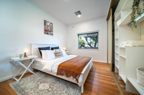 Un dormitorio con una cama y un escritorio y una ventana. en Jupiter - 3BR WiFi BBQ, en Thebarton