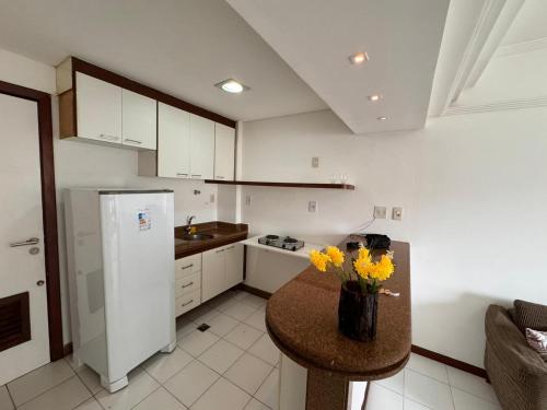 uma cozinha com um frigorífico branco e uma mesa com flores amarelas em Pituba sol flat em Salvador