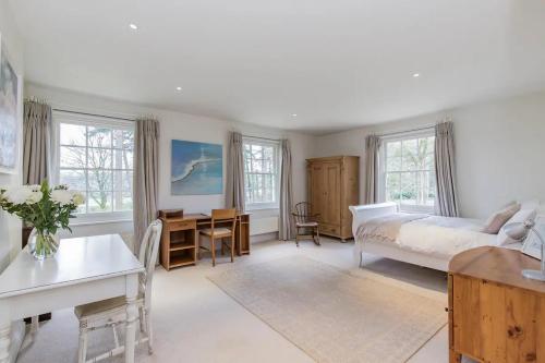 a bedroom with a bed and a desk and windows at Isle Hill in Newbury