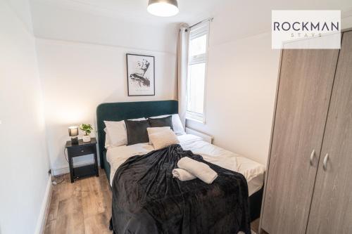 a bedroom with a bed with a green headboard at Northumberland House 5 Bed Apartment Close To Beach with Parking by RockmanStays in Southend-on-Sea