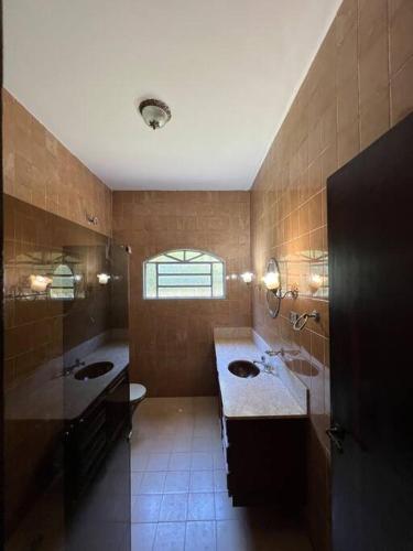 een grote badkamer met 2 wastafels en een raam bij Sítio Paraíso Uberaba in Uberaba