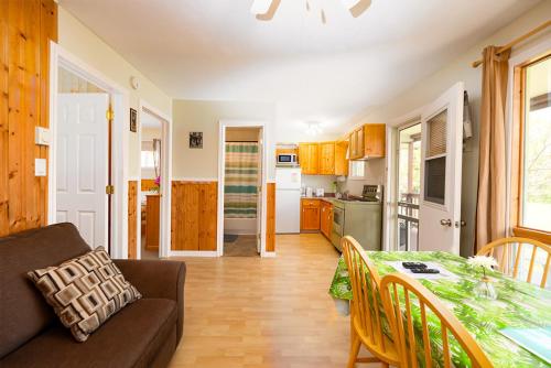 a kitchen and a living room with a table and a couch at Fiddler's Green Country Cottages in Brackley Beach