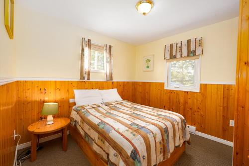 1 dormitorio con 1 cama y 1 mesa con lámpara en Fiddler's Green Country Cottages, en Brackley Beach