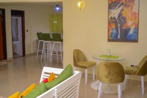 カンパラにあるRIMA 3BRM Cozy Apartmentのリビングルーム(ソファ、テーブル、椅子付)