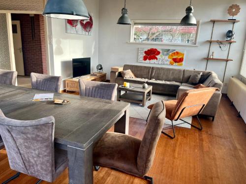 een woonkamer met een tafel en stoelen en een bank bij Beach House Wantveld Noordwijk aan Zee in Noordwijk aan Zee