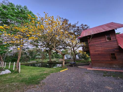 a building next to a pond next to a tree at Cabaña del Lago in Cuatro Esquinas