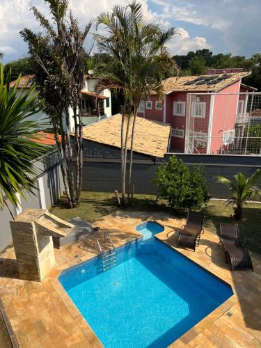 uma piscina num quintal com cadeiras e uma casa em Casa 331 em Jaguariúna