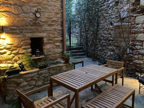 un patio avec une table et des chaises en bois et un mur en pierre dans l'établissement 13th Century Stone House, à Faugères